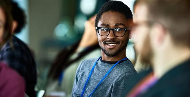 Young man smiling at another conference member