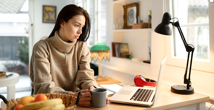 woman with coffee mug in front of a laptop
