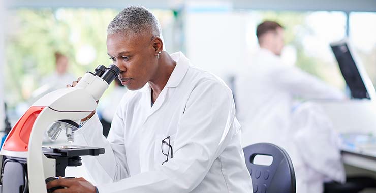 female scientist peering into microscope