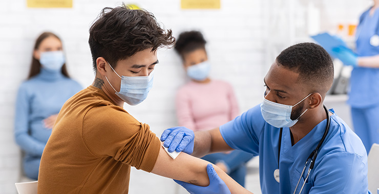 Doctor wiping young man's arm with a gauze