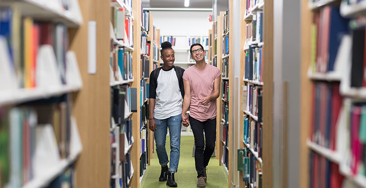 Two young man walking in library aisle