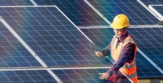 worker in a hard hat adjusting a solar panel