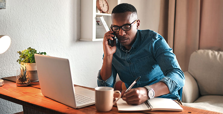 man taking notes while talking on the phone
