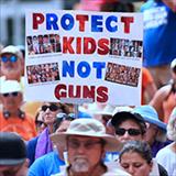 Protesters with a sign reading protect kids not guns.