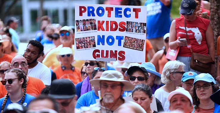 protesters with a sign reading protect kids not guns