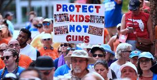 protesters with a sign reading protect kids not guns