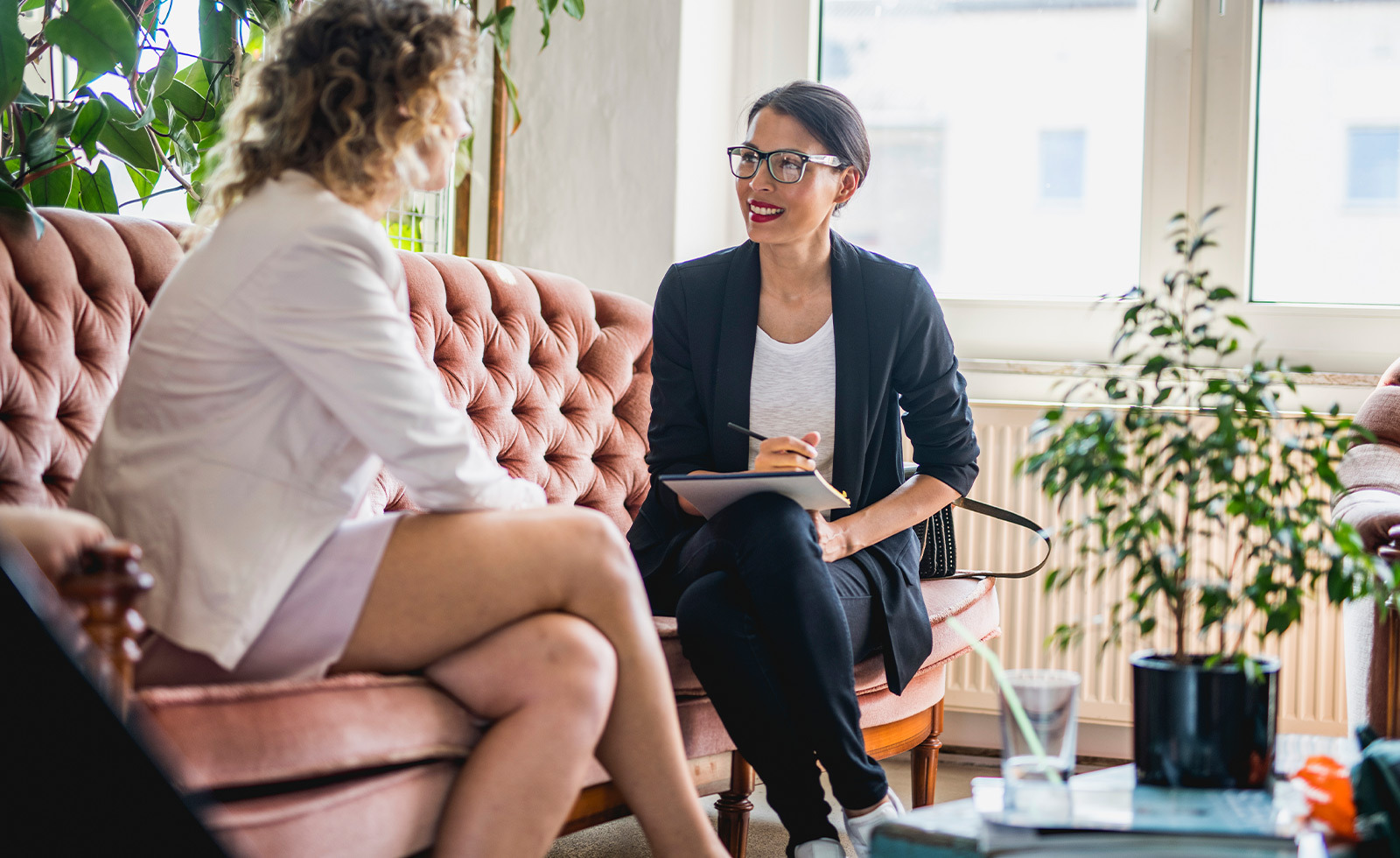 Two women smiling and talking to each other on a couch