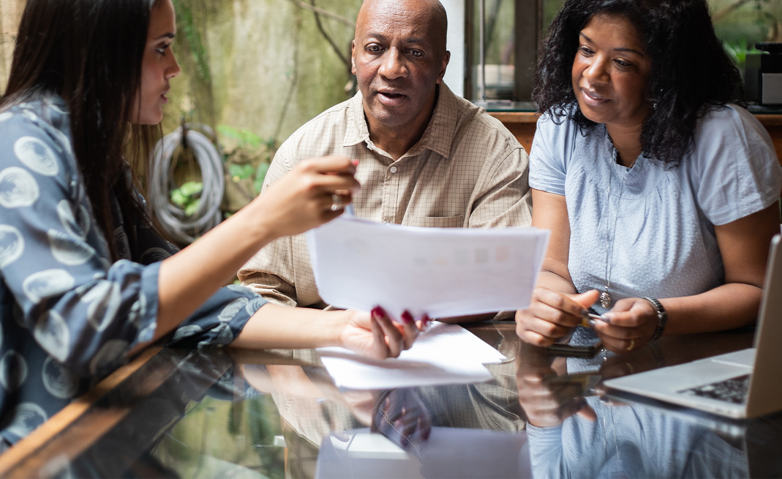 An older couple is looking at a piece of paper being shared by a young professional woman 