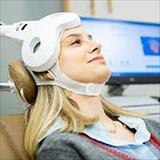 A female patient uses Transcranial Magnetic Stimulation