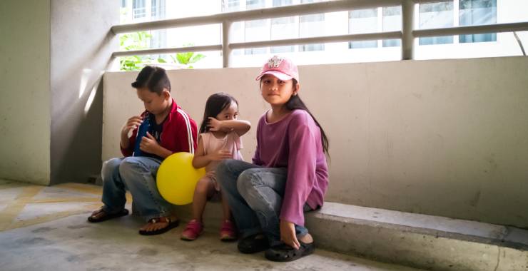 Young children sitting on the ground in a parking lot