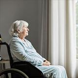 Elderly woman in wheelchair looking out of window