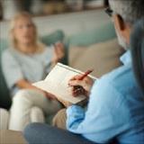 Psychologist takes notes while speaking with patients in a counseling session.