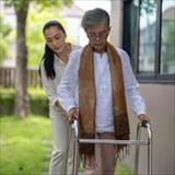 A younger woman assists an older woman using a walker