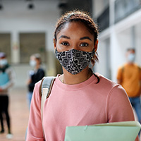 Female student wearing a face mask and holding a binder
