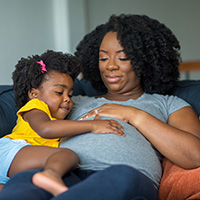 Pregnant mother sitting with her daughter on a couch