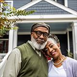 Older couple hugging in front of house