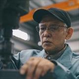 A factory worker operates industrial equipment inside a manufacturing facility.