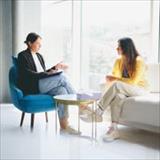 A psychologist and an individual sit across from each other in an office, engaged in conversation.