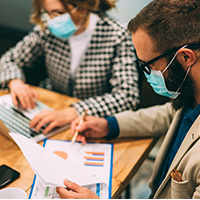 Man in face mask looking at data charts
