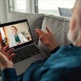 Senior man sitting on sofa and having video call with his doctor