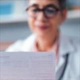 Healthcare professional reviews a document in a clinical office setting.