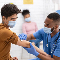 Doctor wiping young man's arm with a gauze