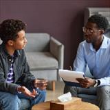 Teenage boy drinking water when talking to adolescent psychologist about his worries and problems