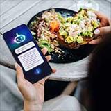 Person holding a smartphone with an AI health app while eating a meal.