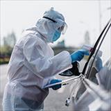 Medical personnel in full PPE equipment checking a drivers temperature
