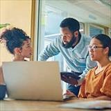 Coworkers gathered around a laptop in an office, engaged in discussion and collaboration