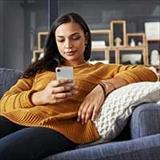 A woman sitting on a couch looking at her smartphone