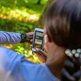 Woman on a nature trail using her smartphone and smartwatch to monitor her vital signs