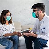 Doctor and patient sitting down wearing face masks