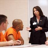 professional speaking to two young men in prison uniforms