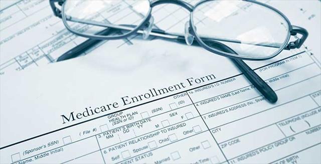 Medicare enrollment form with pair of glasses on top