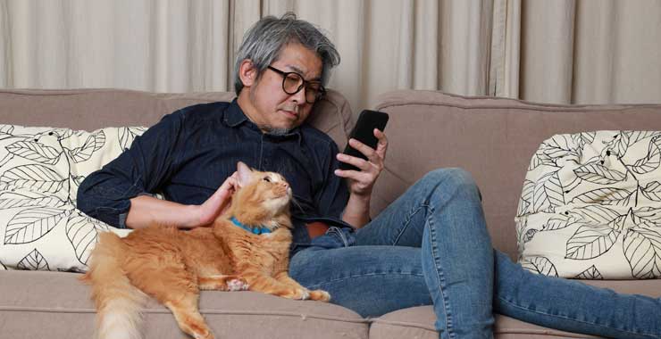Man with his cat looking at smartphone 