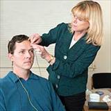 A practitioner attaches sensors (electrodes) to a patient's head to monitor brainwave activity.