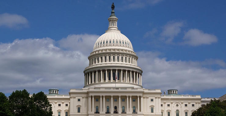 The United States Capitol building in Washington, D.C., viewed from the front under a partly cloudy sky.