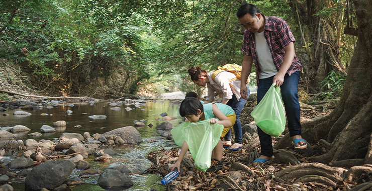 Family picking up trash near river
