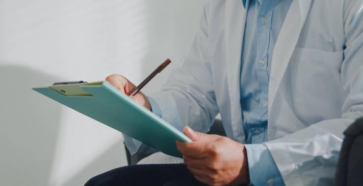 A medical professional writes notes on a clipboard.