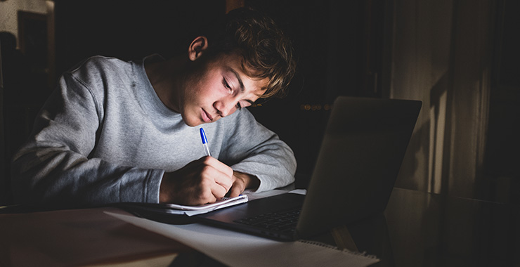 Boy working on schoolwork in front of a laptop