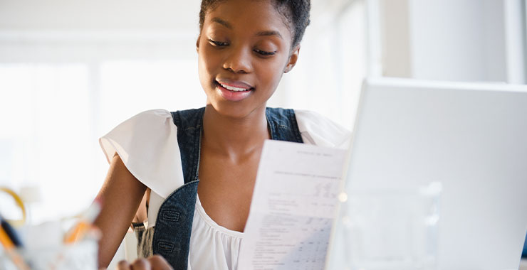 Woman at her computer holding a document