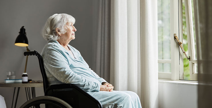 Elderly woman in wheelchair looking out of window