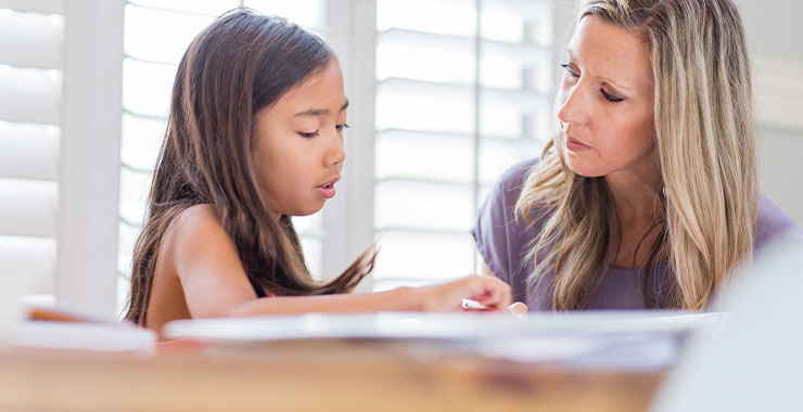 Teacher reviewing work with young student of color