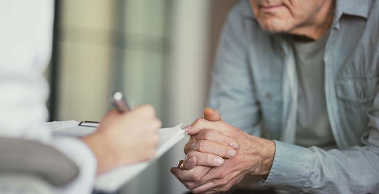 Psychologist attentively taking notes during a session with an older adult