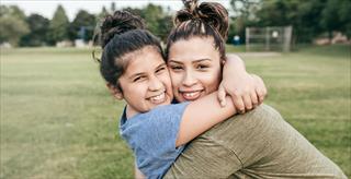 Mom and daughter hugging on a field