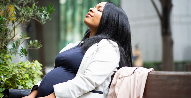 Pregnant Black woman sitting on bench