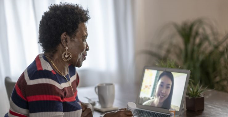 An older adult using her laptop to video call with a healthcare provider
