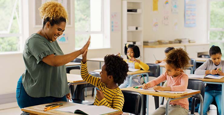 Black teacher high fiving a Black student
