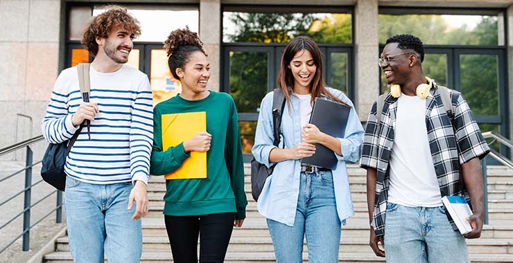 Group of high school students chatting happily outside of building